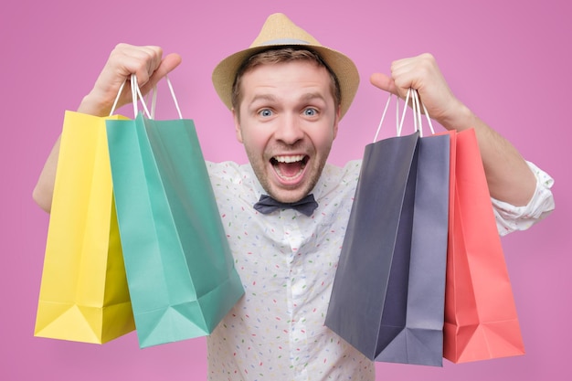 Man holding pile of bags with gifts with shock