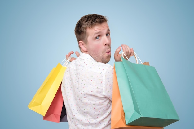 Man holding pile of bags with gifts with shock