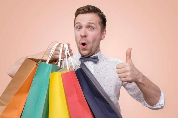 Man holding pile of bags with gifts with shock