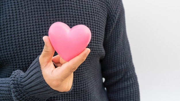 Man holding a pink heart on white 