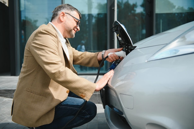 Man holding power connector for electric car