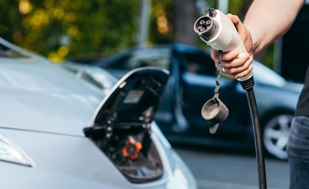 Man holding power supply cable at electric vehicle charging station Closeup