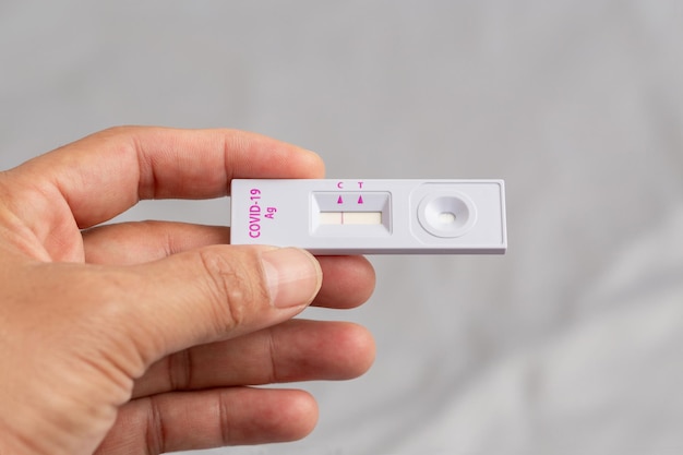 Man holding rapid antigen test kit with the negative result during swab COVID-19 testing. Lockdown and Home Isolation concept.