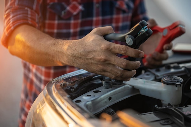 Man holding red and black battery cable for charging the car Car Repair and maintenance concept