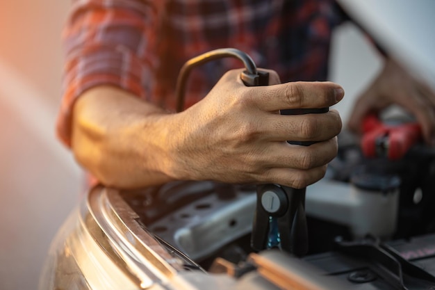 Man holding red and black battery cable for charging the car Car Repair and maintenance concept