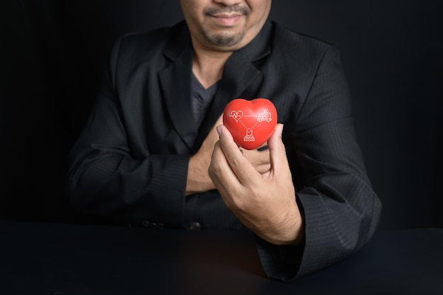 Man holding red heart and feel chest pain on black background