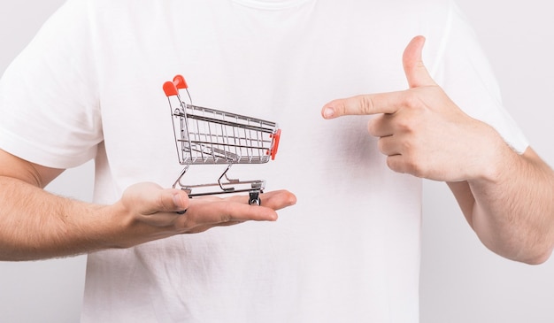 Man holding shopping cart in his hand and point to it