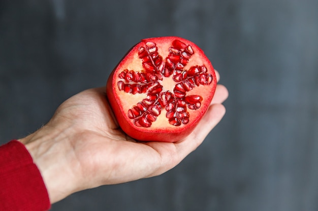 Man holding and showing cut ripe pomegranate