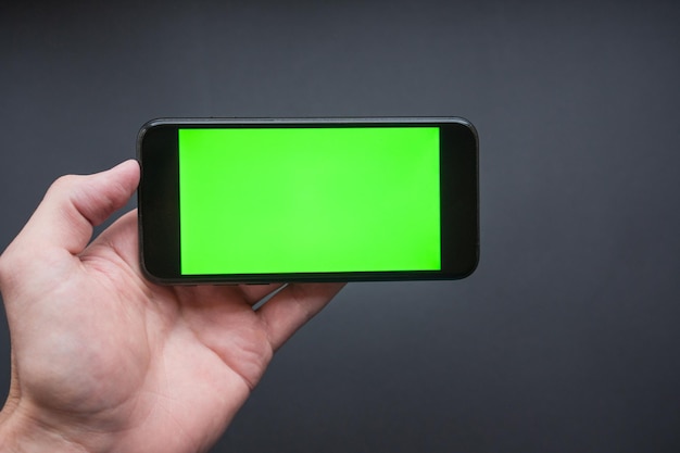 Man holding a smartphone Green Screen Smartphone in Landscape Mode