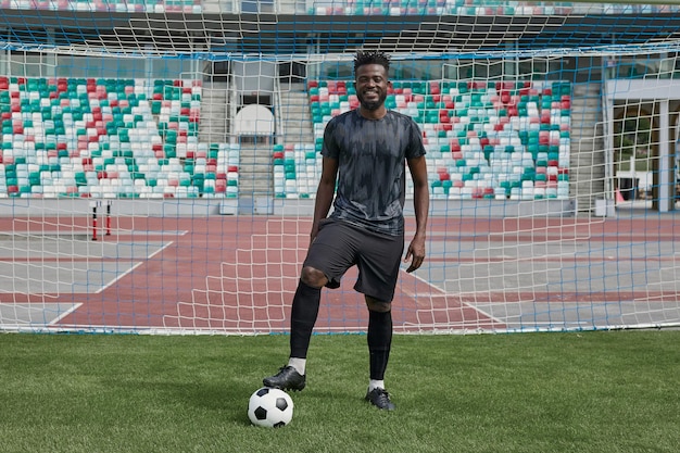 Man holding soccer ball with his foot in the stadium