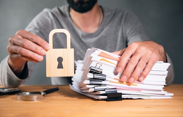 Photo man holding stack of paper and lock