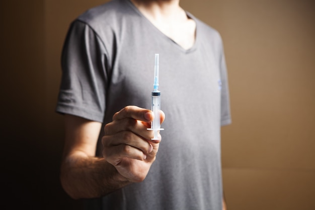 Man holding a syringe. addiction concept on brown background