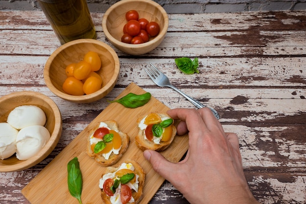 Photo man holding tasty bruschetta with mozzarella tomato basil and oil ingredients on the background