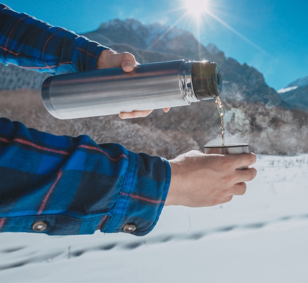 Man holding a thermos in on a snowy mountain