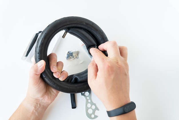 A man holding of the tire of an electric scooter fixing a puncture the master applies a patch