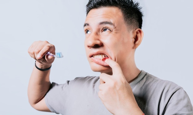 Man holding toothbrush with gum pain isolated People holding toothbrush with gum problem isolated Young man with gingivitis holding toothbrush People holding toothbrush with gum pain