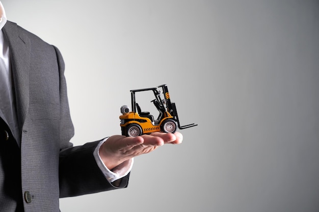 Man holding toy forklift against gray background