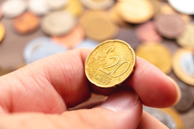 A man holding a twenty cent coin of euro money