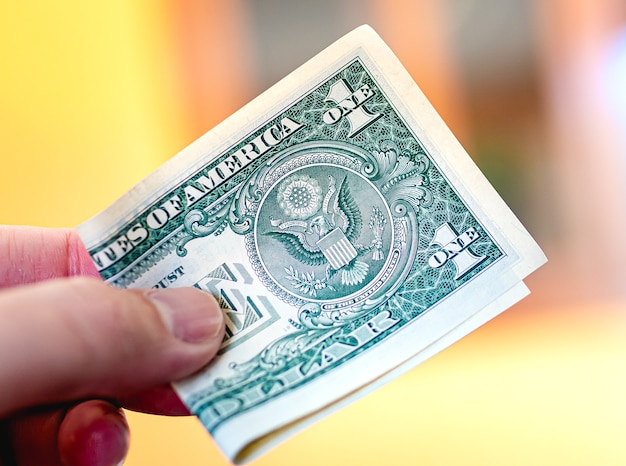 a man holding a US dollar bill in his hand in a dark environment