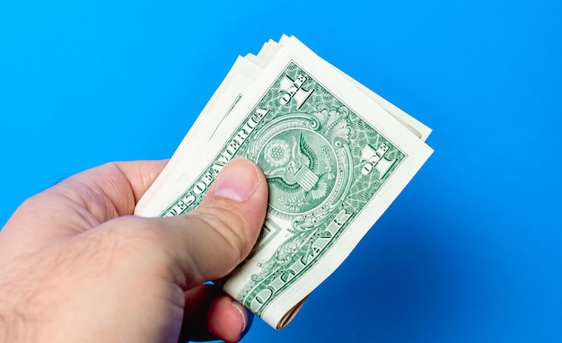 a man holding a wad us dollar bills with blue background 