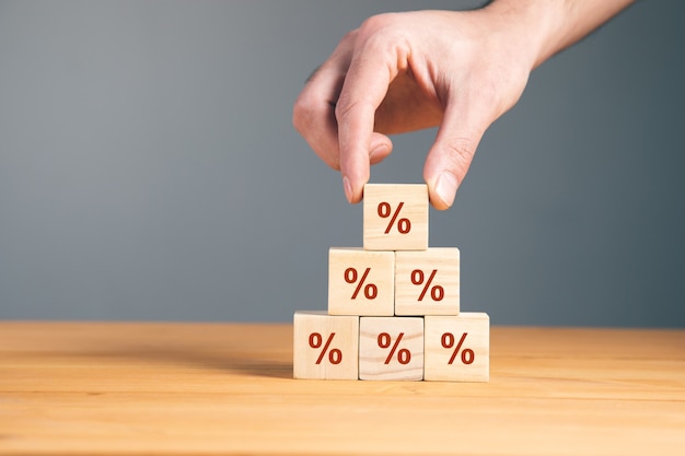 Man holding wooden blocks with percent.