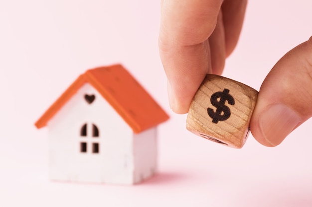 Photo man holding a wooden cube with dollar symbol on the background of house real estate value concept