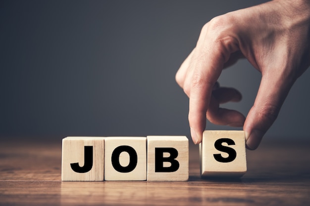 man holding wooden cubes and jobs text