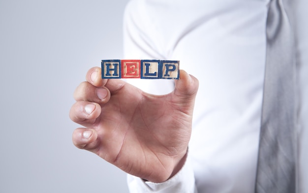 Man holding a wooden cubes with the message Help.