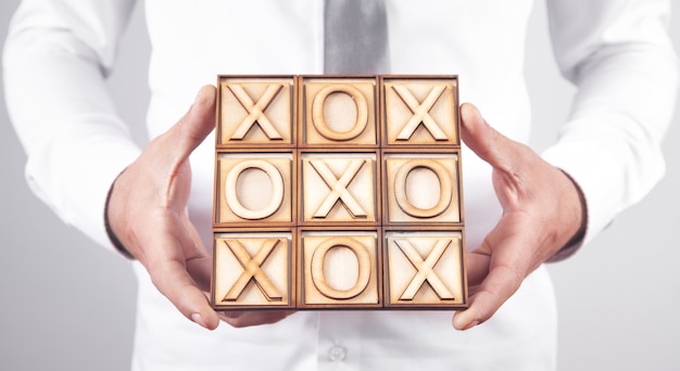 Man holding wooden X, O game.