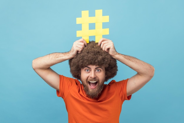 Man holding yellow hashtag sign board on head dreaming about target tagging posts on his website