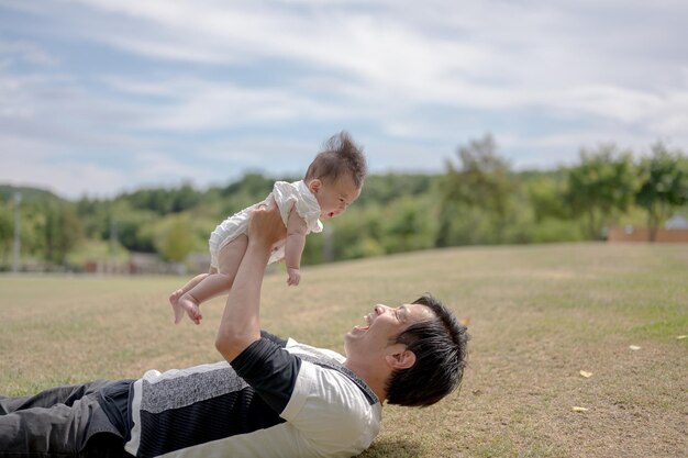 A man holds a baby up in the air, with the word love on the front of his face.