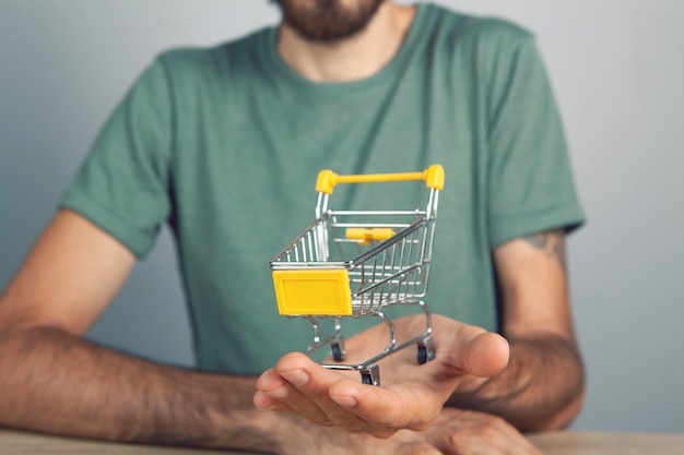 A man holds a cart in his hand. shopping concept on gray background