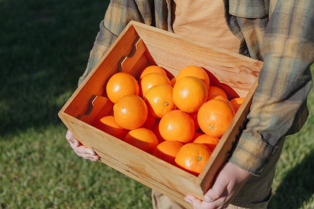 A man holds a crate of oranges