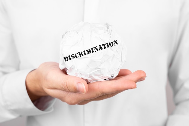 Photo man holds crumpled paper with text discrimination in his hands