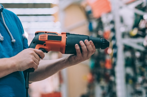 man holds an electric drill in his hand for drilling