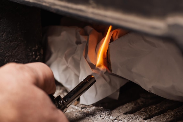 Man holds a gas lighter and makes a fire in the solid fuel boiler Heating warmth winter renewable fuel concept