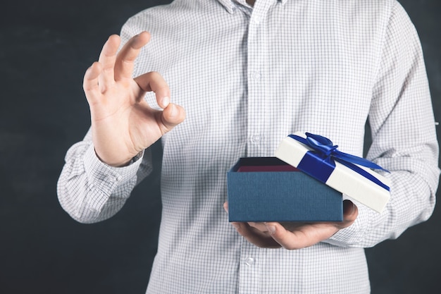 Man holds a gift in his hand and shows a good sign