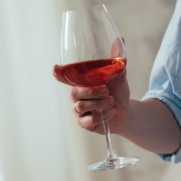 A man holds a glass of red wine in his right hand