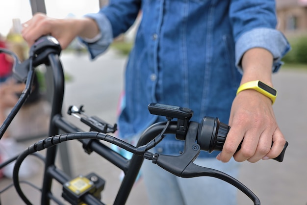 Man holds handlebars of black bicycle in street.