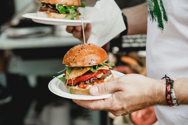 Man holds in his hand burgers at a burger feast dinner hamburger food feast party big burger