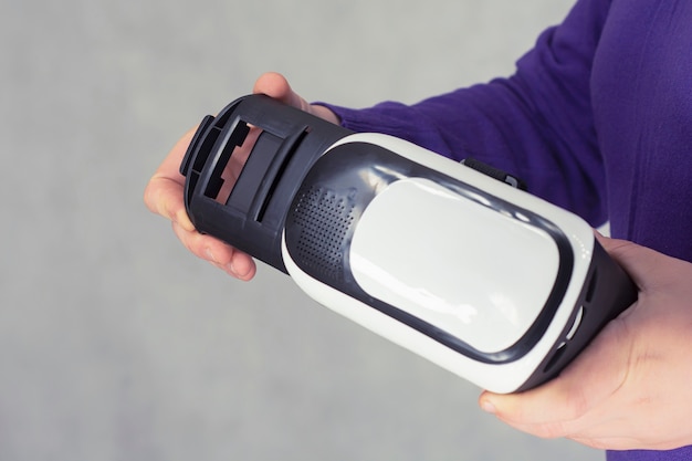 Photo man holds in his hands glasses for virtual reality and 360-degree video. vr helmet for the smartphone on a light background.