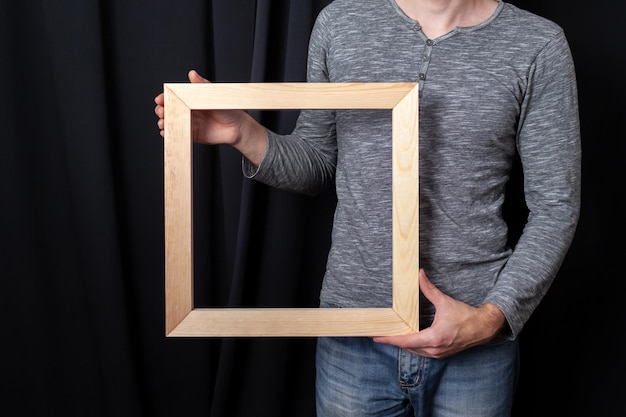 Photo a man holds in his hands a square wooden subframe for stretching canvas