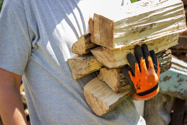 A man holds a lot of chopped firewood in his hands