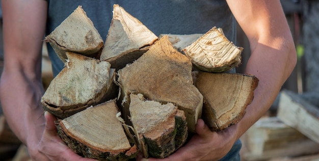 A man holds a lot of chopped firewood in his hands