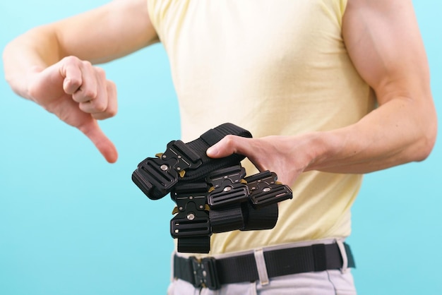 A man holds many black canvas belts with a black fast open metal male buckle and shows his thumb down Weapon Cloth Belt Military Buckle Clothing Equipment Canvas Protection Strap War Wear