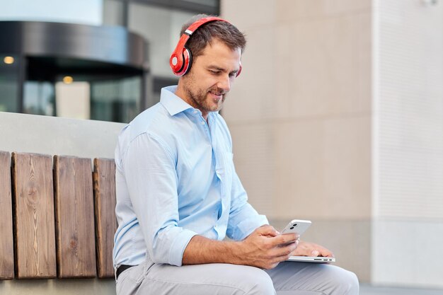 Photo a man holds an online meeting while sitting on the street with a laptop and headphones