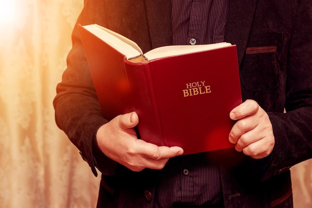 A man holds an open Bible in his hands Reading and studying the Bible