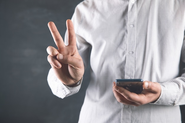 A man holds a phone and shows a good sign .