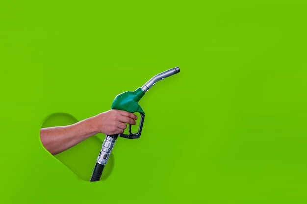 Man holds a refueling gun in his hand for refueling cars isolated on a green background Gas station with diesel and gasoline fuel closeup