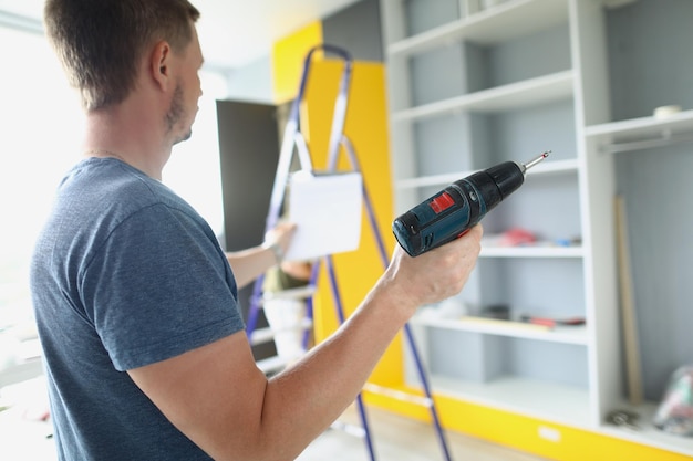 A man holds a screwdriver and instructions for selfassembly of the cabinet installation of